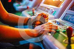 Player`s hands holding a joystick and buttons while playing on a white arcade video game