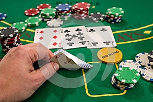 player shows two aces play card on a green table in a casino wirh chips. gambling