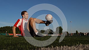 Player sitting on the grass and bouncing a soccer ball by feet