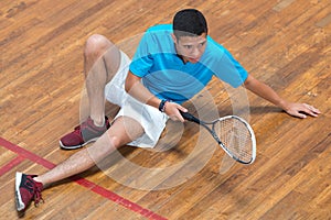 Player with squash ball and racket relaxing after training