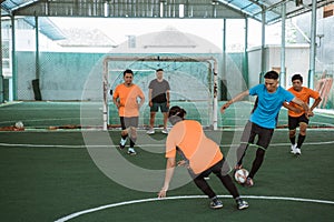 Players in blue uniforms dribble past players in orange uniforms