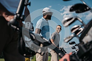 Players going to the golf course, bag with clubs at foreground