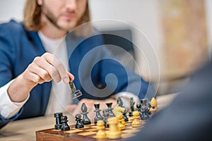 Players hand with chess piece above board