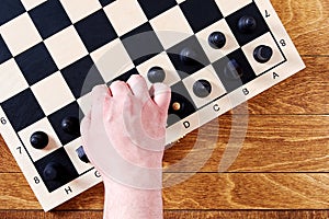 Players hand take a black pawn to do a chess move on the board