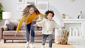 Playful afro american family mother and son running and playing in living room at home