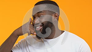 Playful afro-american man showing call sign, flirt gesture, mobile communication