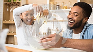 Playful afro girl having fun with dough while cooking