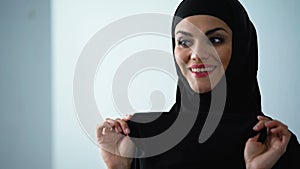 Playful arab woman covering face by hijab and smiling, female happiness, flirt