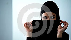 Playful arab woman covering face by hijab and smiling, female happiness, flirt