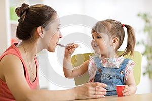 Playful baby girl spoon feeding her mother