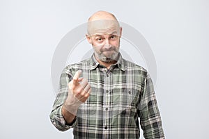 Playful bearded adult showing come here gesture with index finger and smiling