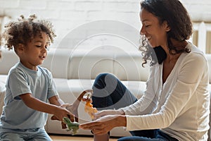 Playful biracial mom play toys with little son