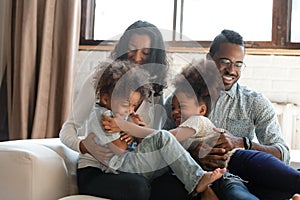 Playful biracial parents play tickle little kids