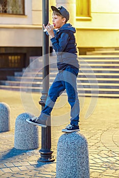 Playful boy eats ice cream standing on stone pillar