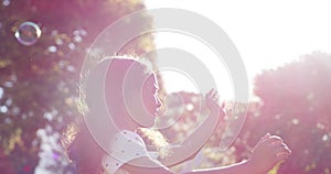 Playful, carefree and happy young girl playing with bubbles outside on a sunny summer day. Cute little female child