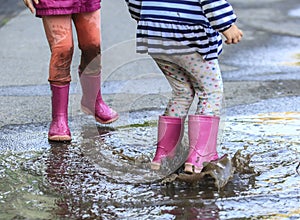 Playful child jump into puddle in boot after rain