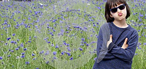 Playful child pouting for skeptical body language, flower meadow background