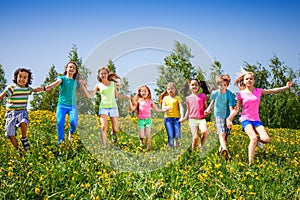 Playful children run, hold hands in green field