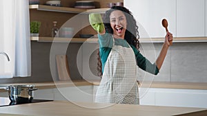 Playful comical woman arabian girl suddenly appears jump in the kitchen surprise effect funny startle wears oven mitt