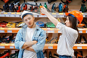 Playful couple choosing tools in hardware store