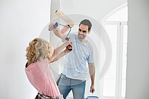 Playful couple fighting while painting new house