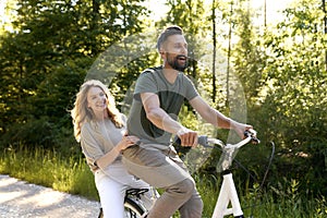 Playful couple having fun on a bike in the woods