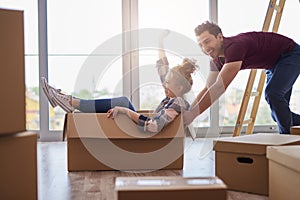 Playful couple having fun with boxes during move house