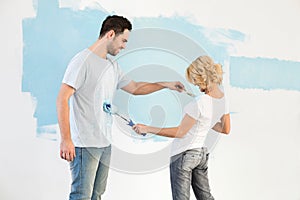 Playful couple painting each other in new house