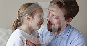 Playful daddy telling secret to happy little daughter girl