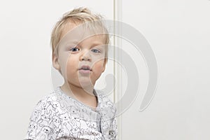 Playful disheveled cute baby looking at camera against white background. Copy space