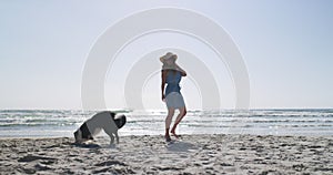 Playful, dog and summer with woman at the beach for vacation, freedom and nature. Pets, holiday and training with person