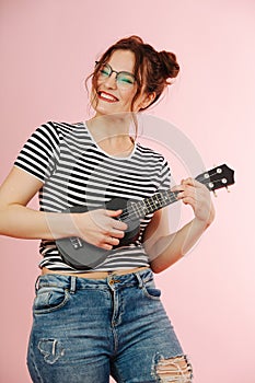 Playful eccentric woman with black ukulele over pink background
