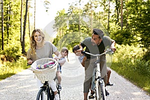 Playful family having fun on a bicycles in the woods