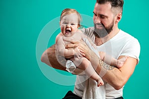 Playful father carrying his smiling infant child on neck over blue background