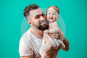 Playful father carrying his smiling infant child on neck over blue background