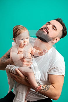 Playful father carrying his smiling infant child on neck over blue background