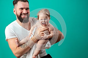 Playful father carrying his smiling infant child on neck over blue background