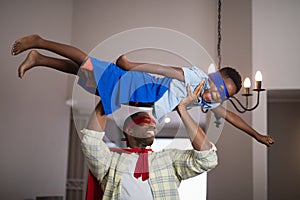 Playful father and son in superhero costume at home