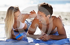 Playful flirtation. A young couple lying together on a towel at the beach.