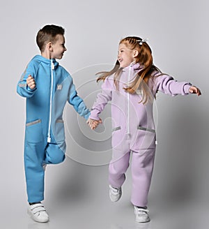 Playful frolic kids boy and girl in blue and pink jumpsuits with are running together looking at each other