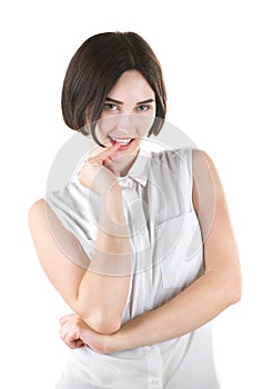 A playful girl. A brunette lady isolated on a light background. A communicative young woman. Smiling girl biting her finger.