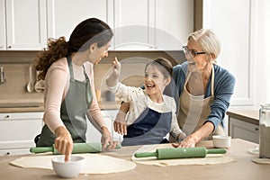 Playful girl, happy mom and granny enjoying baking, having fun