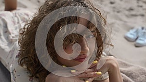 Playful girl touching beach sand lying on mat close up. View gentle woman hands.