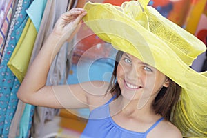 Playful Girl Tries on Yellow Hat at Market