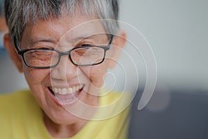 Playful gray hair woman laughing while looking at smartphone as video calling.