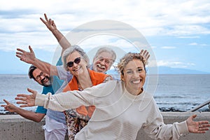Playful group of family having fun together in outdoor excursion at sea, smiling carefree. Parents, son and daughter-in-law