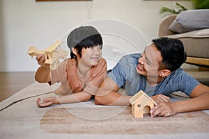 Playful and happy Asian little boy playing a wooden figure model with his dad