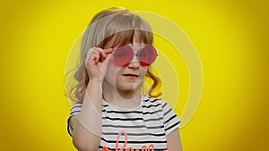 Playful happy kid girl in sunglasses blinking eye, looking at camera with smile, winking, flirting