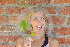 Playful happy woman holding up fresh green leaves