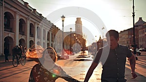 Playful happy young couple is jumping down the street and laughing.